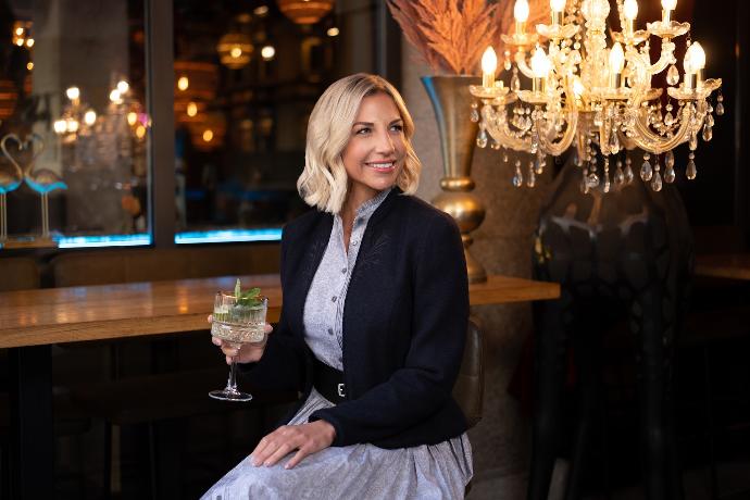 Frau in eleganter Trachtenmode mit einem Cocktailglas in der Hand